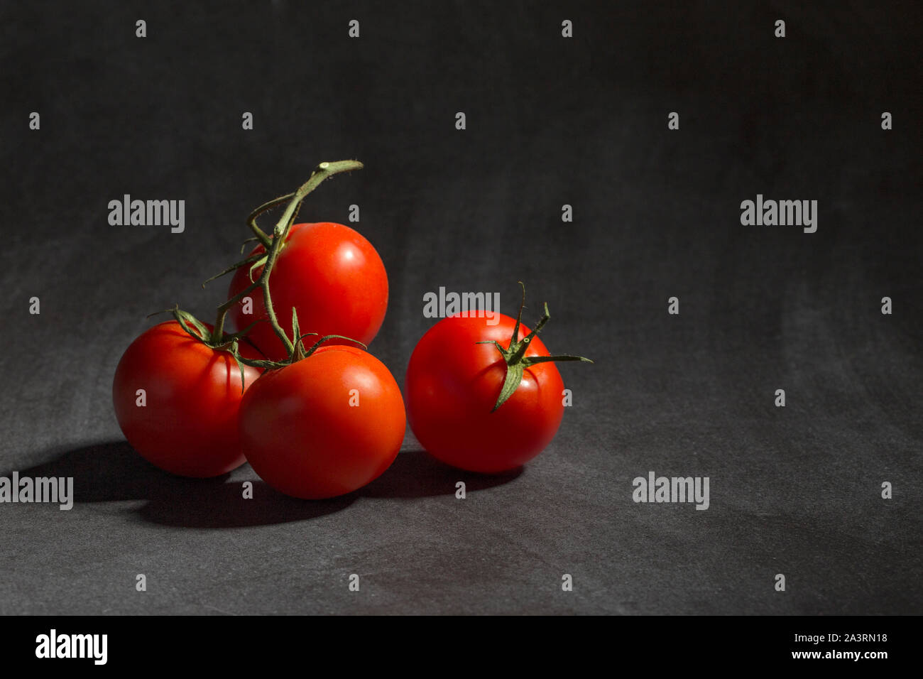 Les tomates de vigne sur le fond noir. Banque D'Images