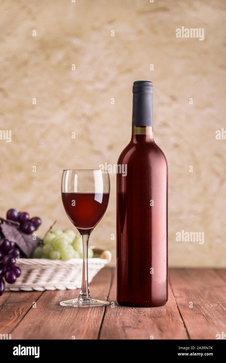 Verre à vin rouge avec bouteille sur fond de stuc et avec chemin de détourage. Banque D'Images