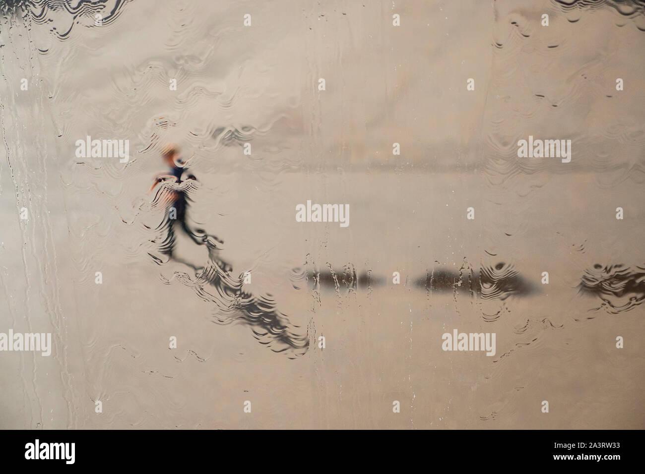 L'homme photographié par le biais d'une fenêtre couverte de pluie Banque D'Images