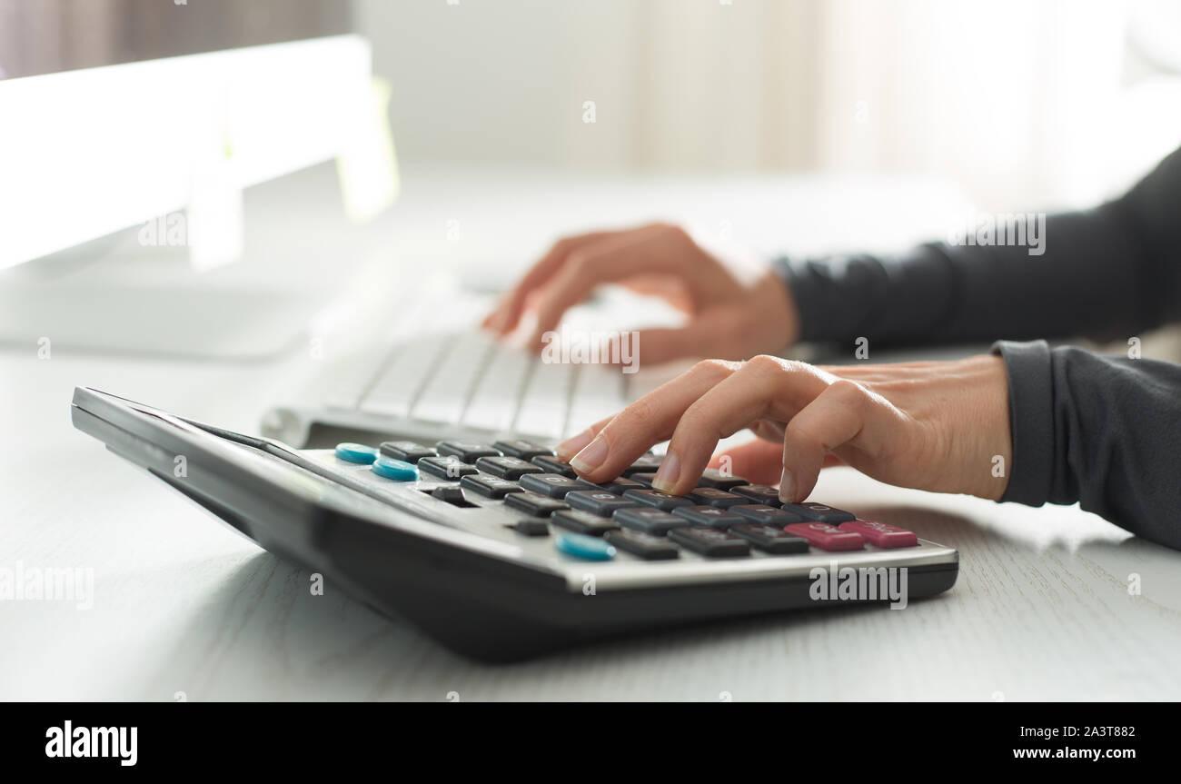 Part d'un comptable compte sur une calculatrice et écrit un rapport financier. Banque D'Images