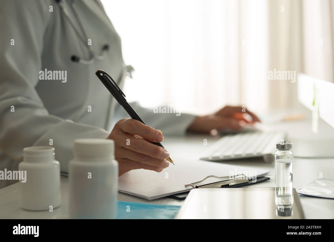 Femme médecin rédige un rapport médical dans le bureau de la clinique. Banque D'Images