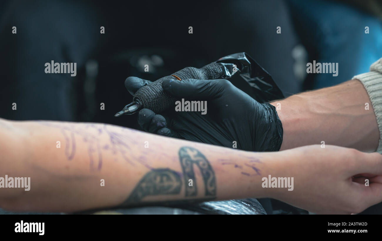 Tatoueur professionnel fait un tatouage sur la main d'un jeune homme, close-up. Artiste de tatouage tatouage tatouage fait en beauté. Processus de tatouage dans tat Banque D'Images