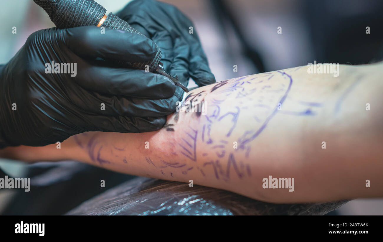 Tatoueur professionnel fait un tatouage sur la main d'un jeune homme, close-up. Artiste de tatouage tatouage tatouage fait en beauté. Processus de tatouage dans tat Banque D'Images