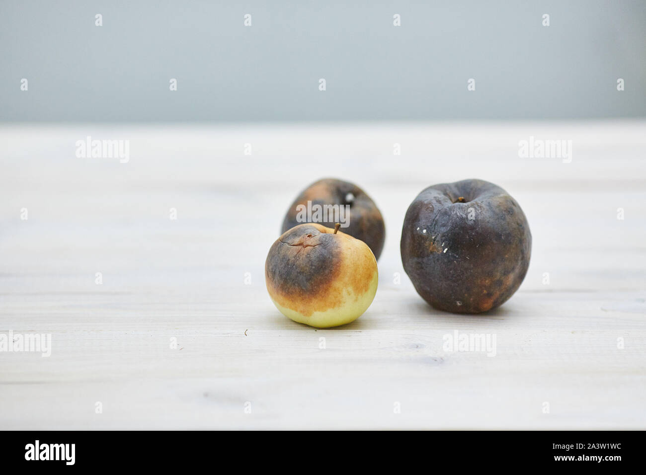 Ugly fruits. Trois pommes pourries sur la table en bois Banque D'Images