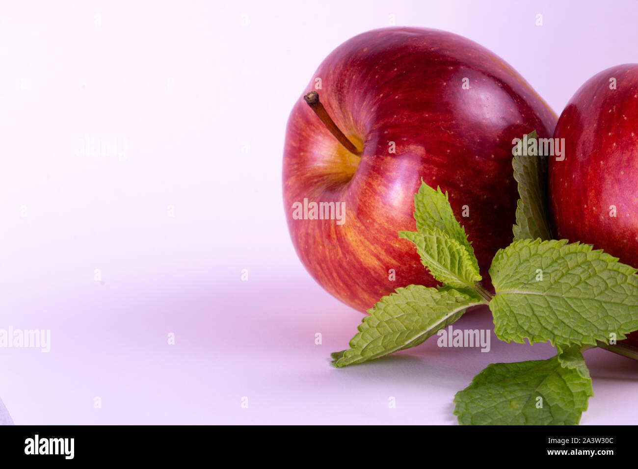 Pommes rouges sur fond blanc, les feuilles de menthe, groupe de deux Banque D'Images