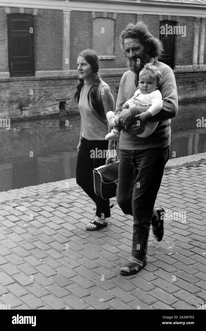 Ein Paar mit seinem Baby spaziert mit un Gracht à Alkmaar, Pays-Bas 1971 entlang. Un couple et leur bébé en flânant un canal ville d'Alkmaar, Pays-Bas 1971. Banque D'Images