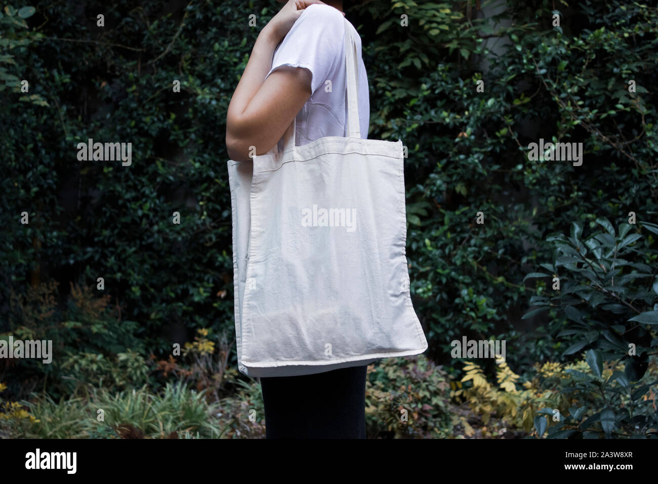 Blanc Blanc Sac en tissu tissu toile shopping sur femme tenant une maquette et le modèle de fond naturel isolé Banque D'Images