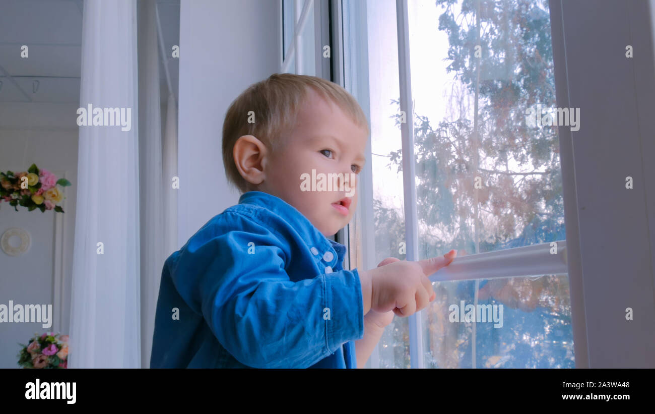 Pensive petit garçon à la recherche d'une fenêtre Banque D'Images