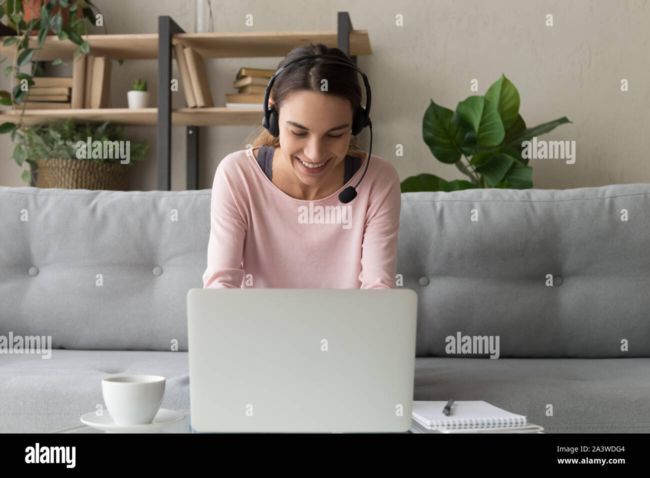 Femme porter un casque sans fil à l'aide d'ordinateur portable à la maison Banque D'Images