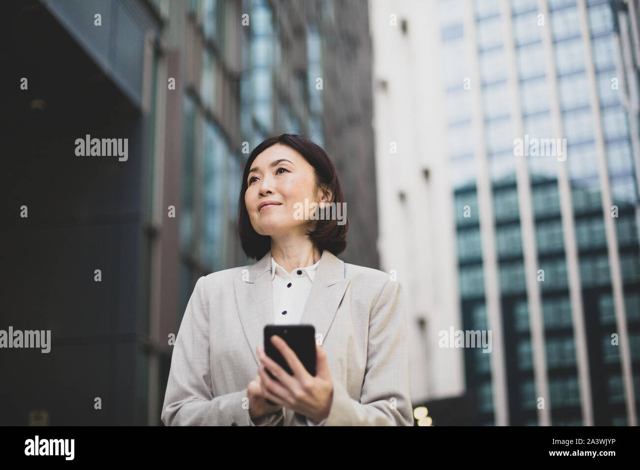 Businesswoman walking in city using smartphone Banque D'Images
