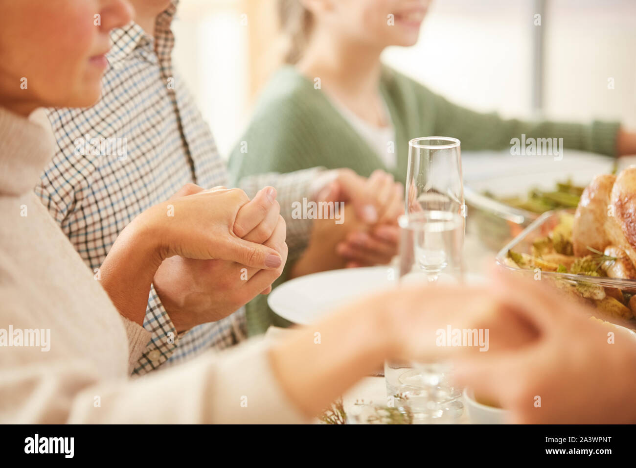 Close-up of family sitting at table de salle à manger et tenir la main ils prier avant le repas Banque D'Images