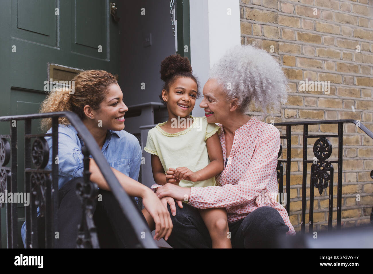 Trois générations de femmes assises à l'extérieur de la maison familiale Banque D'Images