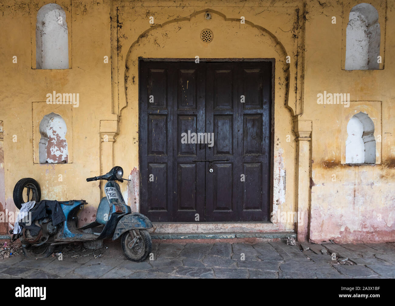 Vieux scooter garé devant une porte en bois, du Rajasthan, Jaipur, Inde Banque D'Images