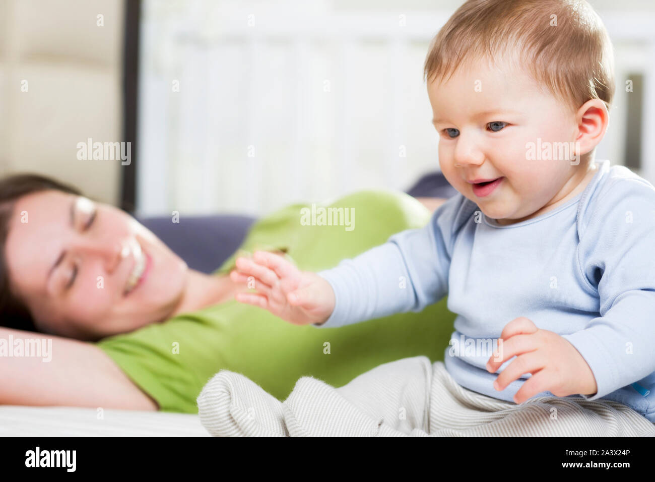 Mère joyeuse et baby boy sitting in bed. Banque D'Images