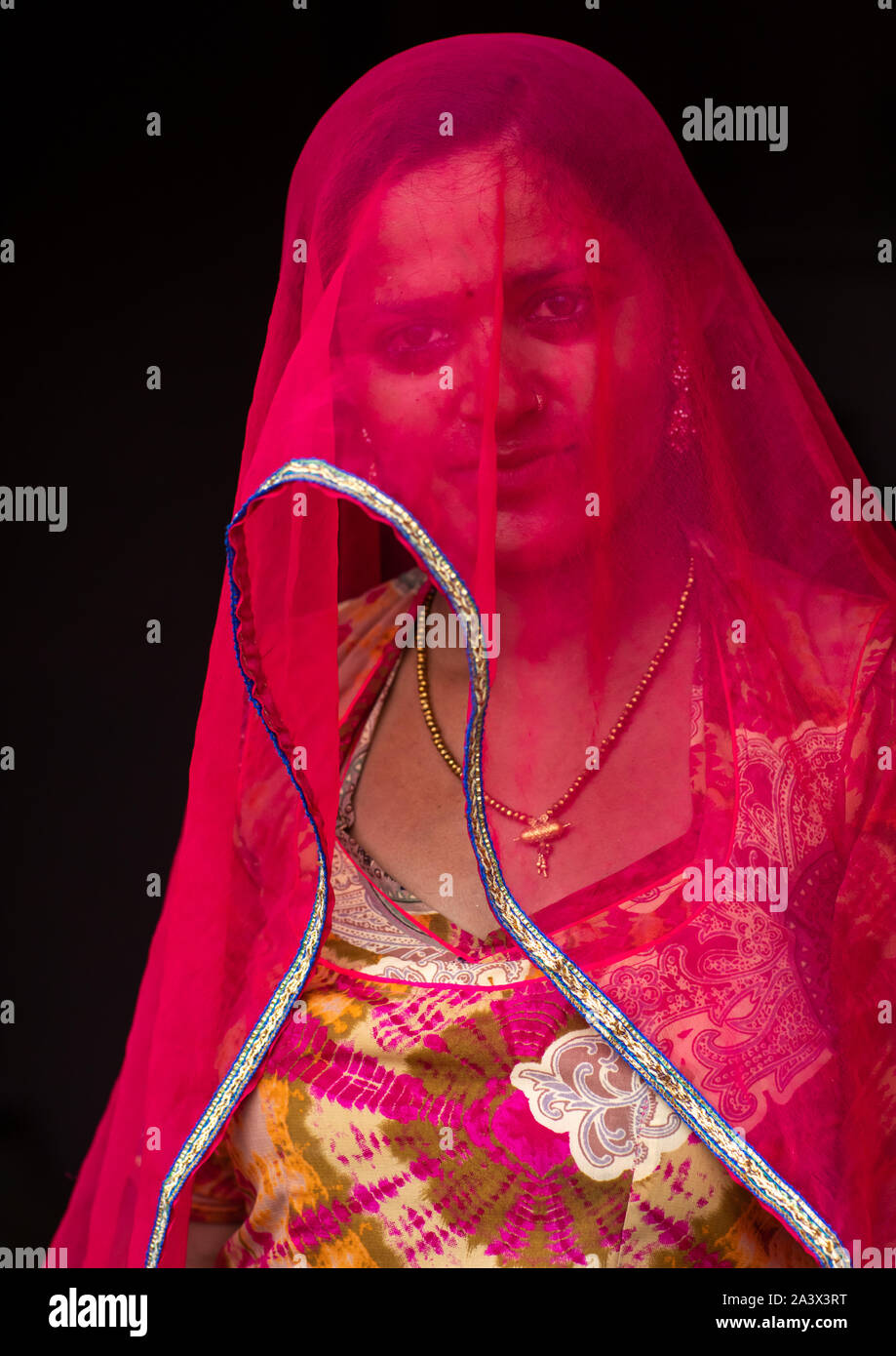 Portrait d'une femme du Rajasthan cache son visage sous un sari rouge, Rajasthan, Jaisalmer, Inde Banque D'Images