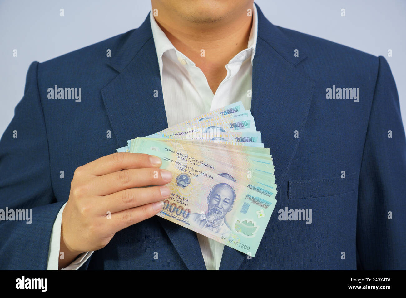 Argent au Vietnam tenir en main business homme portant un costume bleu (République socialiste du Viêt Nam), Dong, VND, payer, l'échange de l'argent sur les vietnamiens bac blanc Banque D'Images