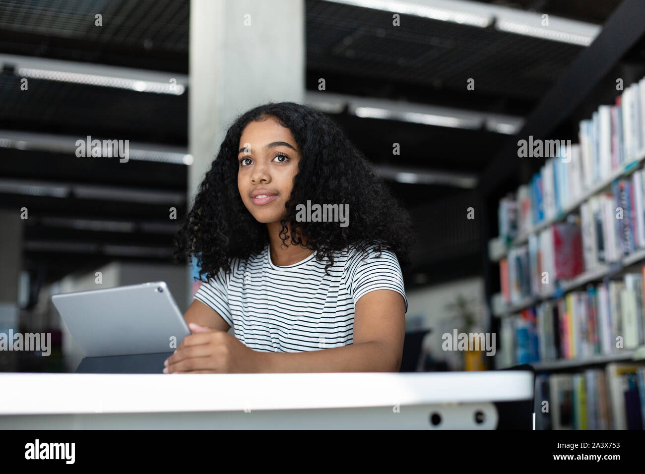 High school african american female student studying with digital tablet in library Banque D'Images