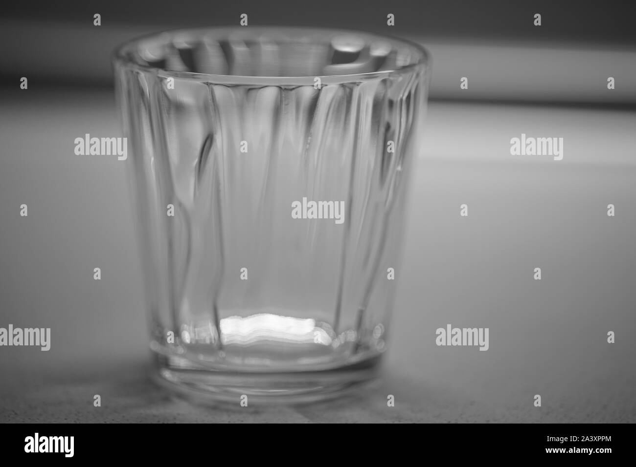 Verre vide pour l'eau sur une table close-up, photo en noir et blanc Banque D'Images