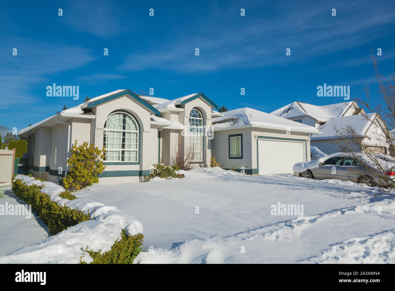 Grande maison d'habitation de luxe avec voiture en stationnement sur l'allée et la neige dans la cour avant Banque D'Images