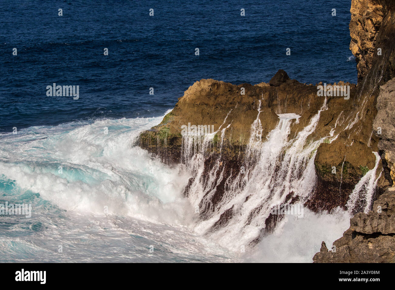 L'eau ruisselait sur falaise sur la rive de la plage Nusa Pendia cassée, l'île, de l'Indonésie. La mousse dans l'avant-plan. Bleu profond de l'océan Pacifique en arrière-plan. Banque D'Images