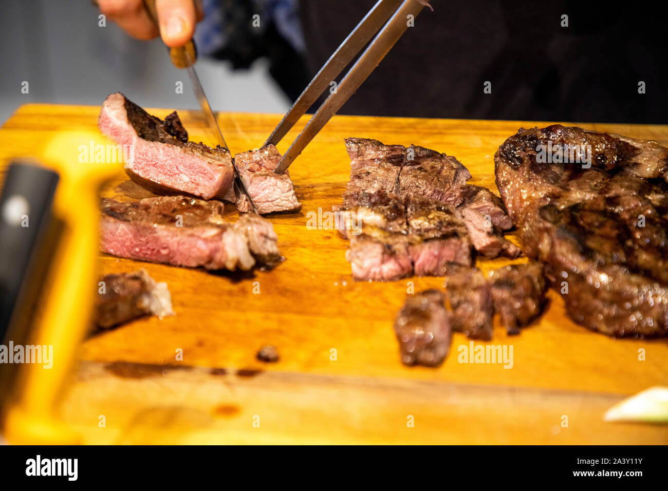 La viande grillée, la viande bovine, est coupée en portions par le cuisinier, Banque D'Images