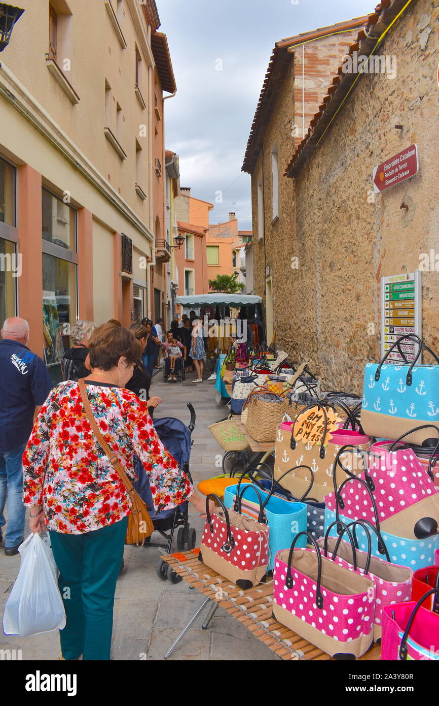 Femme parcourt les étals du marché dans le centre-ville historique. Méditerranée emblématique rose, bleu et brun clair typiquement sacs portés en été par la mer Banque D'Images