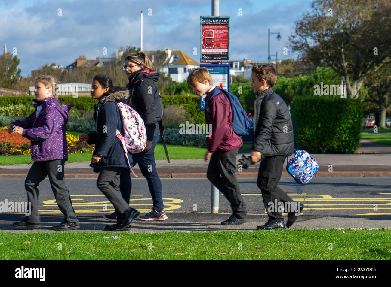 Un groupe d'enfants de l'école britannique en passant devant un arrêt de bus Banque D'Images