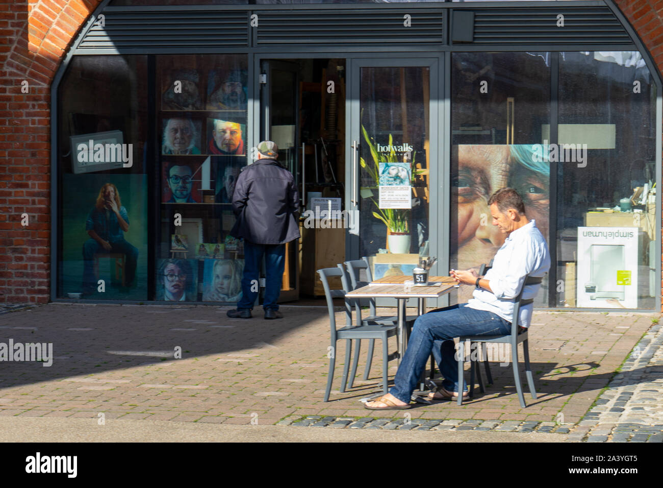 Un homme assis à une table à l'extérieur d'une galerie d'art Banque D'Images
