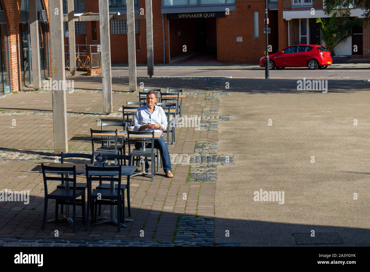 Un homme assis à une table et des chaises à l'extérieur seulement Banque D'Images