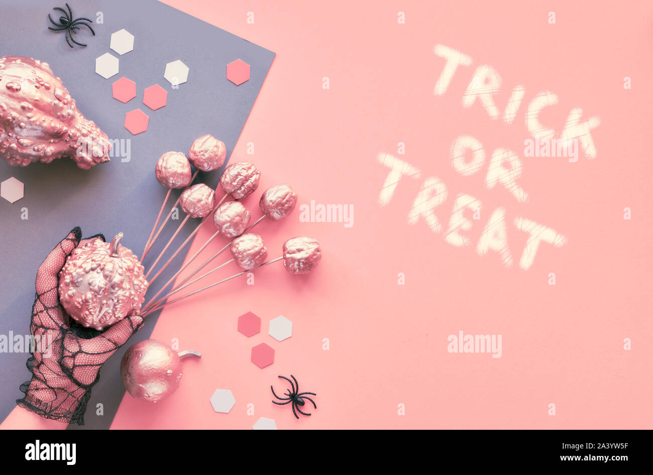 Créations en papier créatif Halloween télévision jeter sur split rose et gris papier fond avec les yeux et les araignées. Les mains dans les gants de maille noire tenue de décorations. Banque D'Images