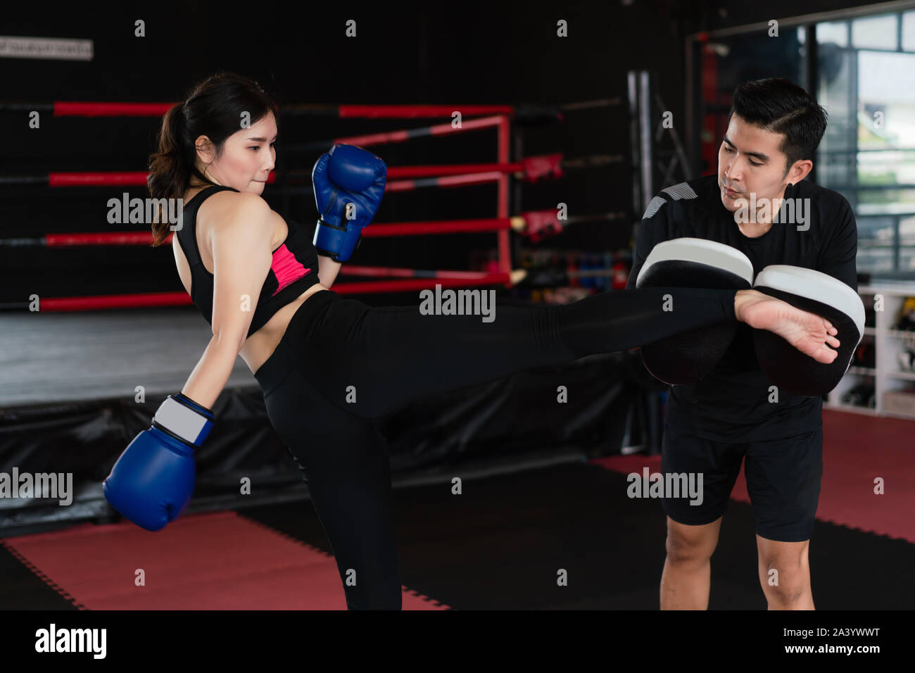 Young Asian woman kicking boxer à pied de formateur professionnel en boxe dans studuim l'arrière-plan de remise en forme à la salle de sport. S'adapter aux modes de vie sportive UN Banque D'Images