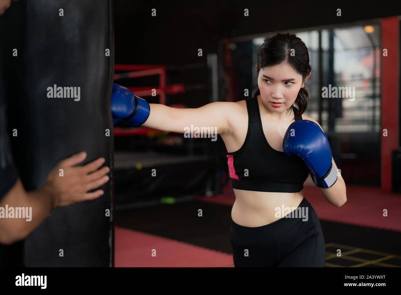 Portrait de jeune femme asiatique confiant boxer bleu avec des gants de boxe, un sac de frappe avec formateur dans professioal de sport. Pour mettre en place sportive lifestyl sain Banque D'Images