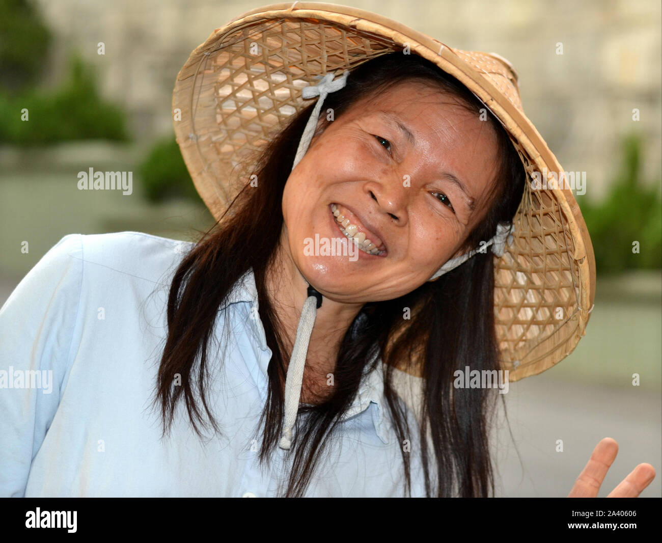 Taiwanais Smiling female gardener porte un chapeau de paille conique de l'Asie et de pose pour la caméra. Banque D'Images