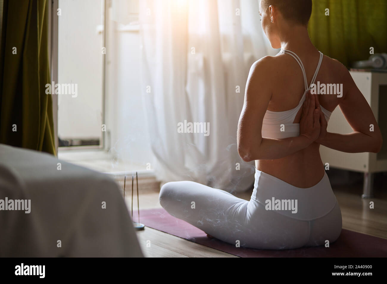 Young woman doing yoga avec namaste derrière le dos, s'asseoir en seïza exercice, vajrasana posture. Dans les vêtements de sport féminin, sujet et blanc, leggins home interi Banque D'Images