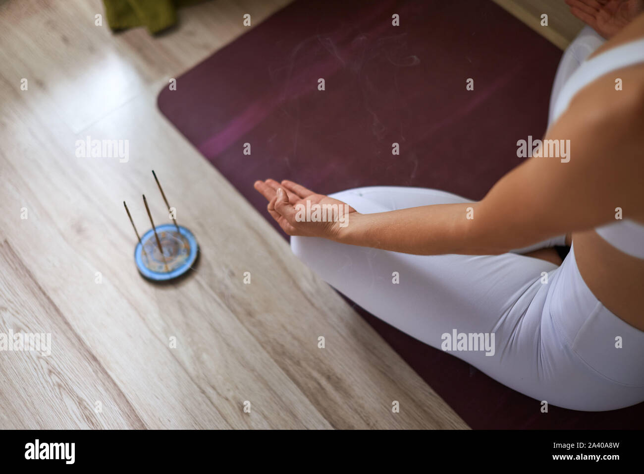 Femme assis à la maison sur le tapis pourpre avec aroma sticks. Concept de soins de santé, Yoga Banque D'Images