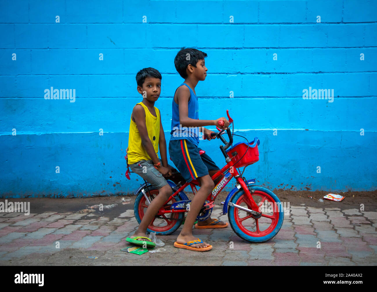 Les garçons indiens d'une bicyclette devant un mur bleu, Rajasthan, Jodhpur, Inde Banque D'Images