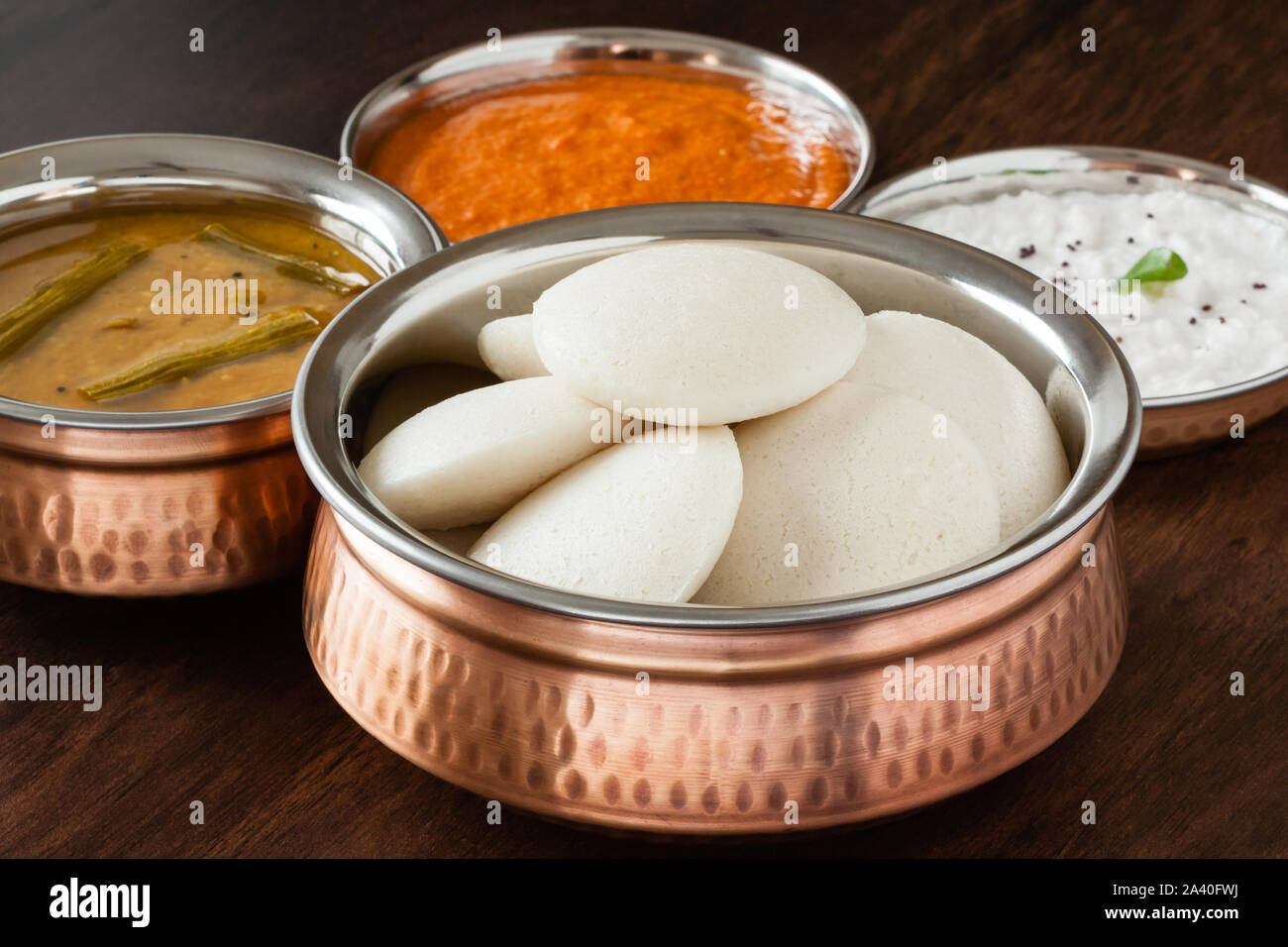 Les bras croisés et chutney indien avec Sambar indien à la vapeur douce - les bras croisés (Idli / gâteau de riz) en cuivre authentique bol. Servi avec sauce tomate et noix de coco Chutney. Banque D'Images