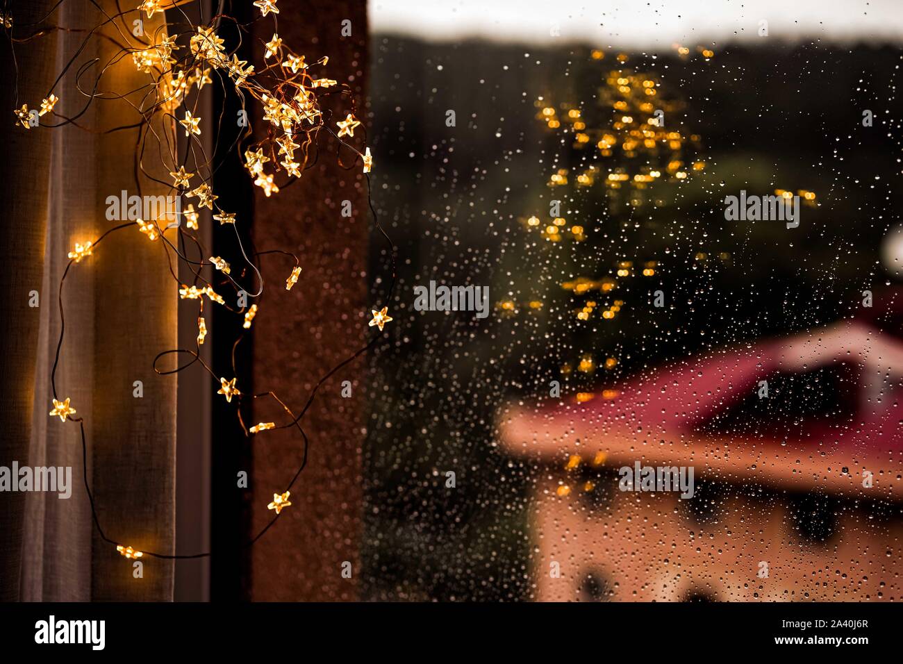 Gouttes de pluie sur la vitre à l'arrière-plan de la ville d'automne. Bokeh chaudes Lumières de flou artistique à l'intérieur de la maison.. Abstrait toile. Gouttes de pluie sur un carreau de fenêtre. Banque D'Images