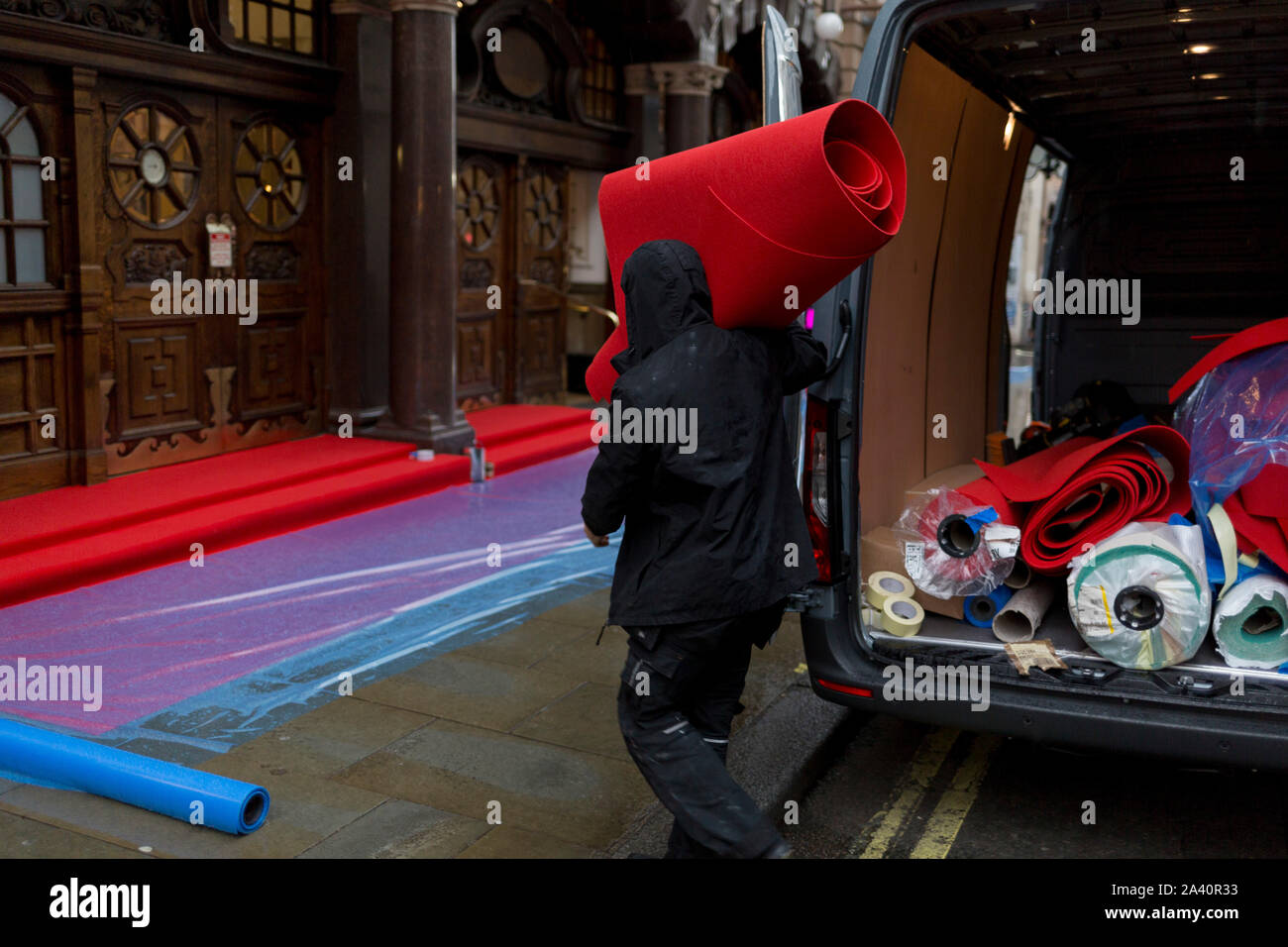 Ouvriers préparer un tapis rouge pluie sur les foules en attente de voir l'English National Opera's soirée d'ouverture d'Orphée et Eurydice au Colisée à Saint Martin's Lane, au 1er octobre 2019, à Londres, en Angleterre. Banque D'Images