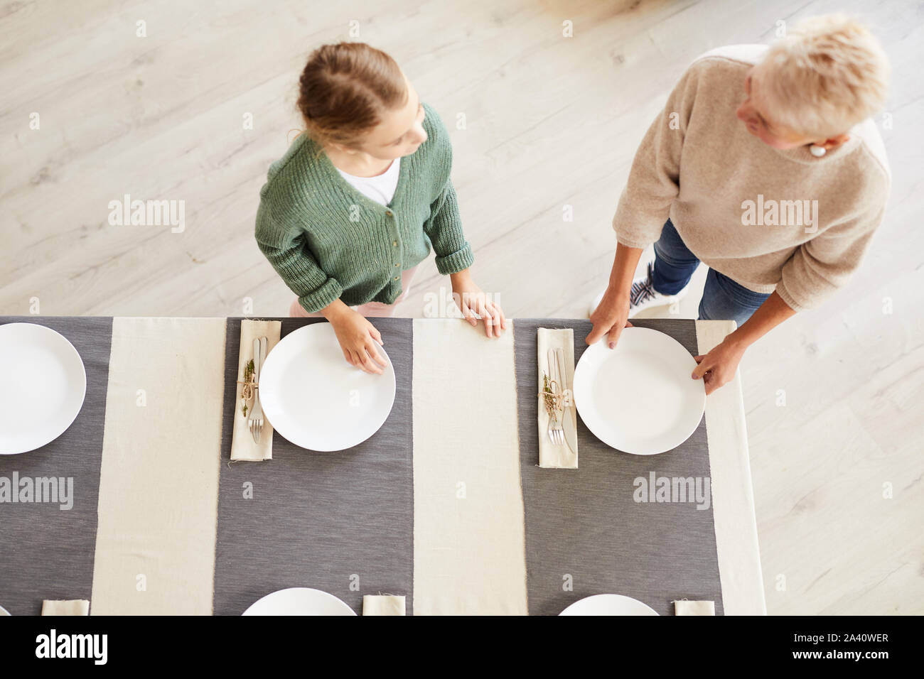 Mère de mettre la table et aider sa fille à elle avant le dîner en famille à la maison Banque D'Images