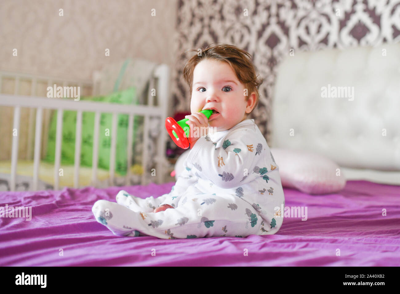 Enfant joue avec ses jouets sur le lit. Le garçon de mordre un jouet sur un lit à la maison Banque D'Images