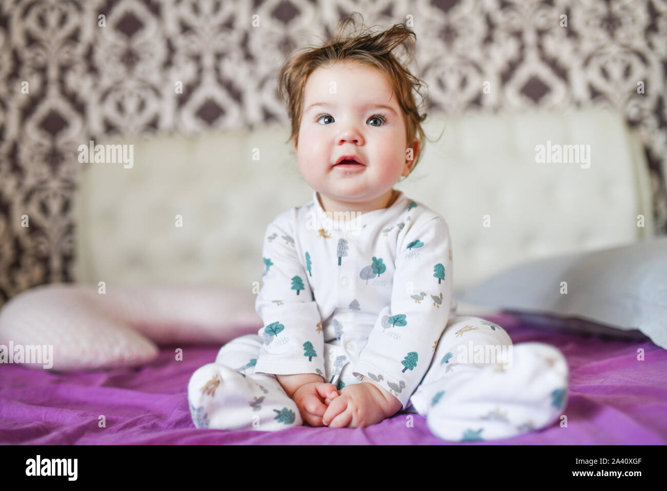 Image aux couleurs d'un happy smiling boy assis sur le lit de l'ameublement. Banque D'Images