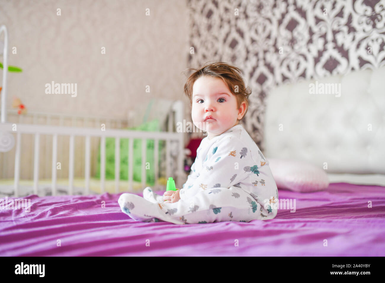 Enfant joue avec ses jouets sur le lit. Le garçon de mordre un jouet sur un lit à la maison Banque D'Images