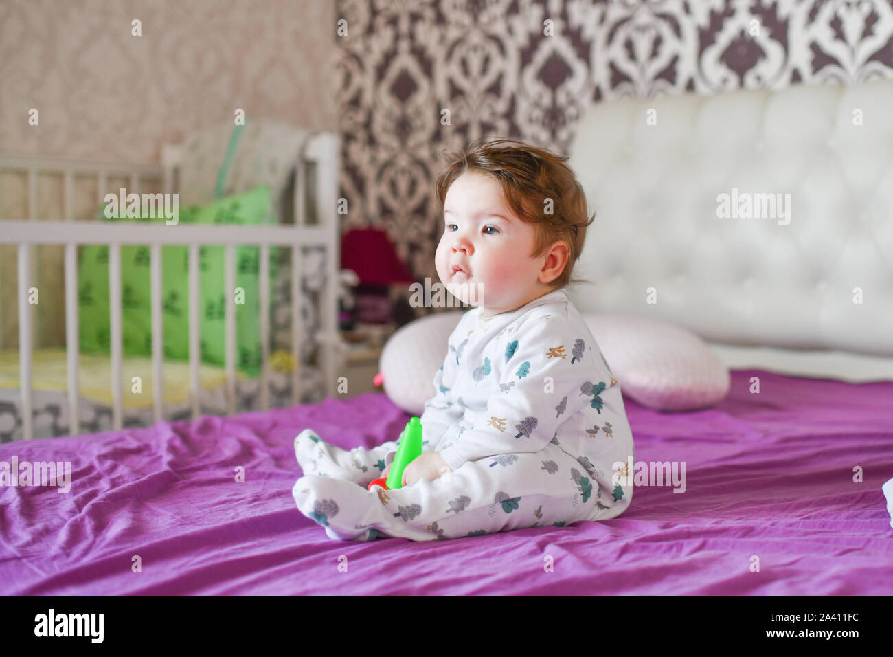 Enfant joue avec ses jouets sur le lit. Le garçon de mordre un jouet sur un lit à la maison Banque D'Images