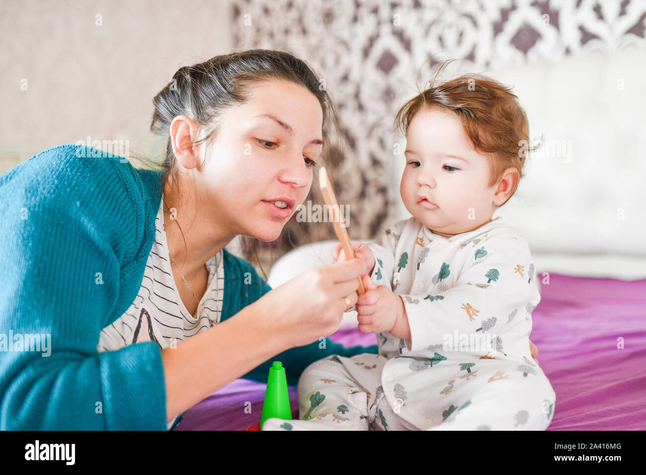 Maman joue avec le bébé sur le lit. Maman joue avec bébé en chambre à l'intérieur. Maman joue avec le bébé dans la chambre à l'intérieur Banque D'Images