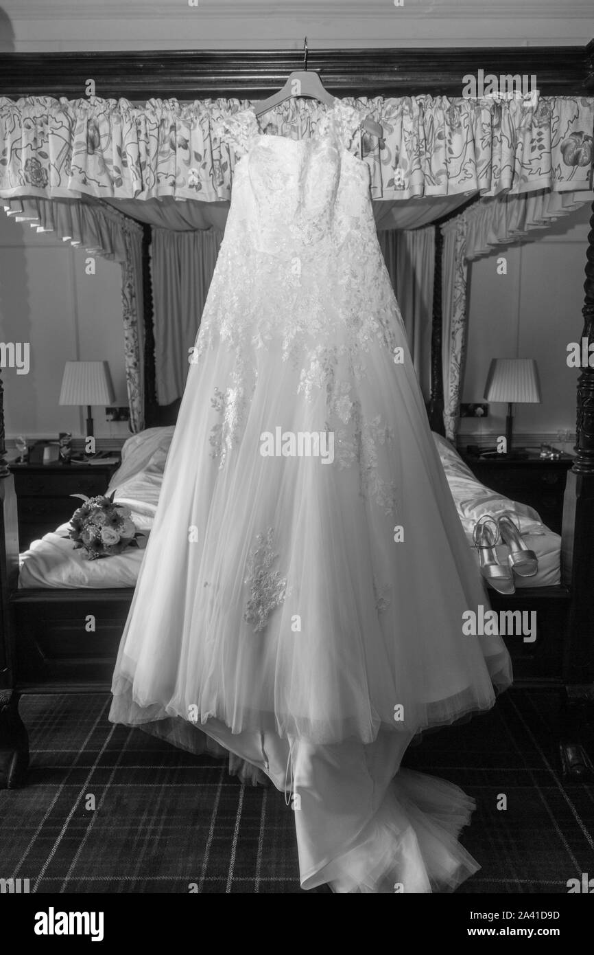 Robe de mariage mariées accroché sur un lit à baldaquin le jour de son mariage avant d'être usés, longue robe de mariée blanche en attente d'être mise sur pied par l'épouse, Banque D'Images