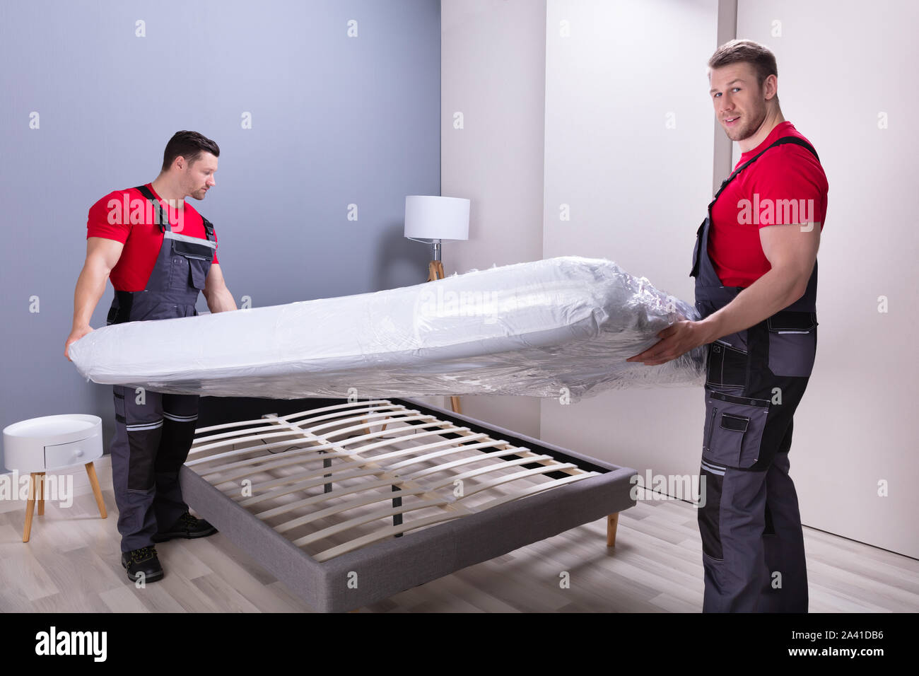 Deux hommes en uniforme des déménageurs professionnels de placer le matelas  sur le lit dans la nouvelle maison Photo Stock - Alamy