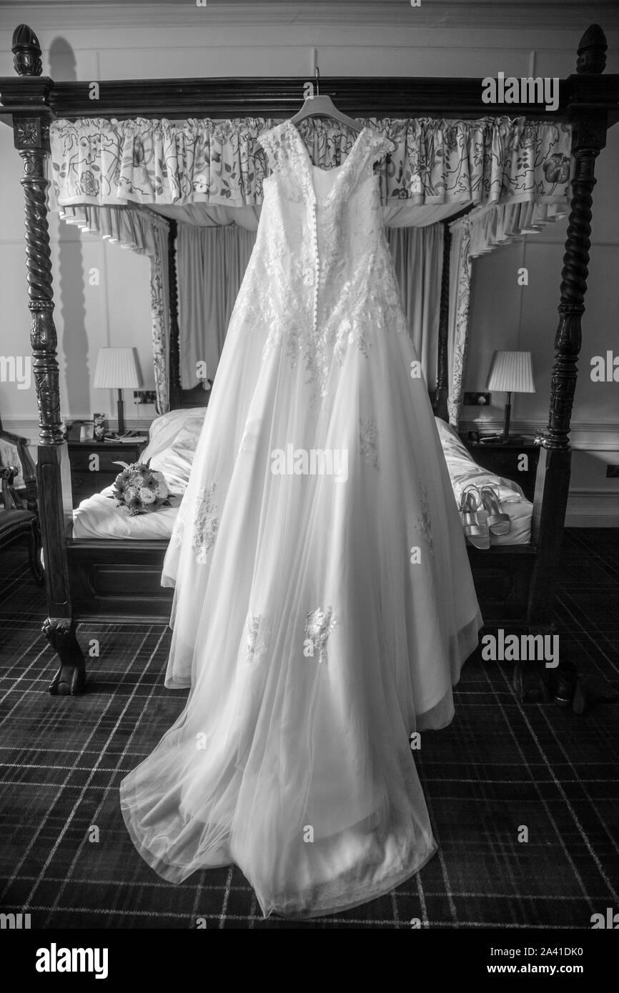 Robe de mariage mariées accroché sur un lit à baldaquin le jour de son mariage avant d'être usés, longue robe de mariée blanche en attente d'être mise sur pied par l'épouse, Banque D'Images