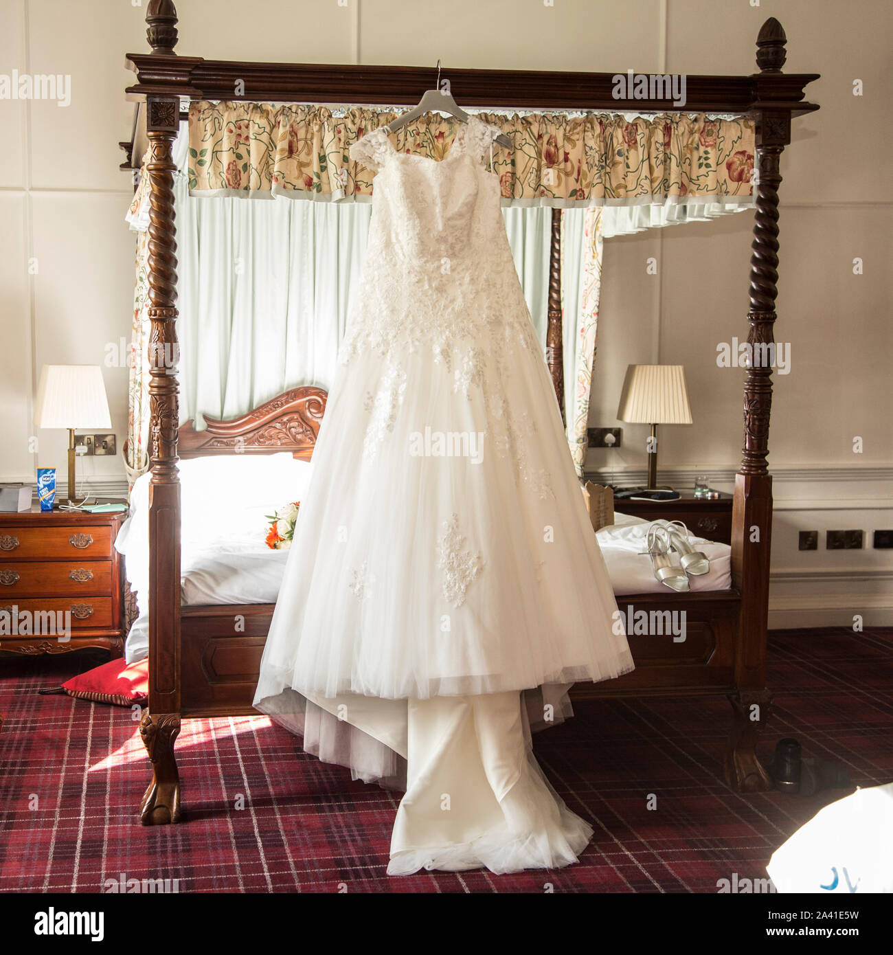 Robe de mariage mariées accroché sur un lit à baldaquin le jour de son  mariage avant d'être usés, longue robe de mariée blanche en attente d'être  mise sur pied par l'épouse Photo