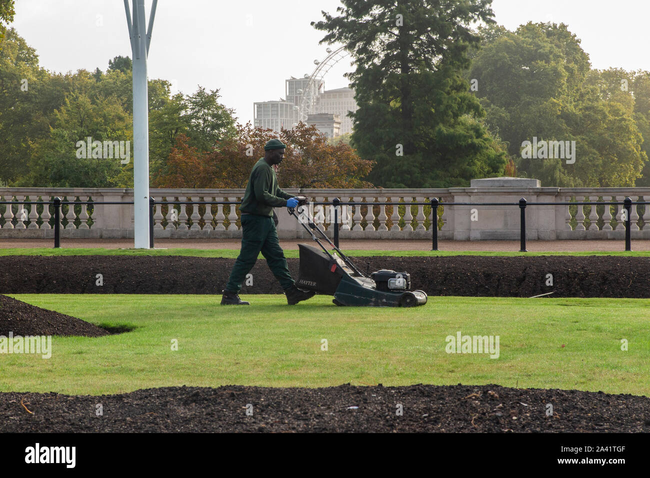 Un jardinier qui tond la pelouse royal au Palais de Buckingham en préparation pour une visite d'état Banque D'Images